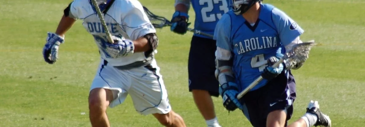 Duke Lacrosse long stick midfielder LSM pursues the NorthCarolina midfielder carrying the ball
