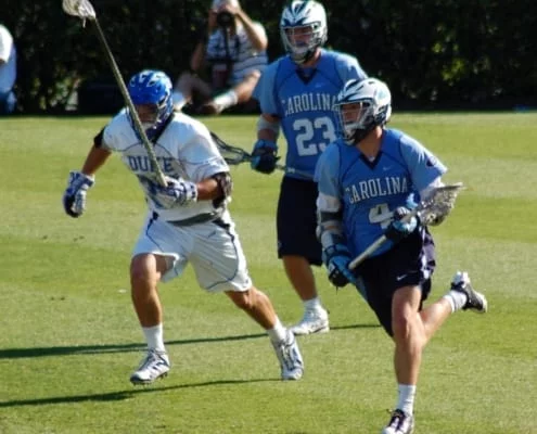 Duke Lacrosse long stick midfielder LSM pursues the NorthCarolina midfielder carrying the ball