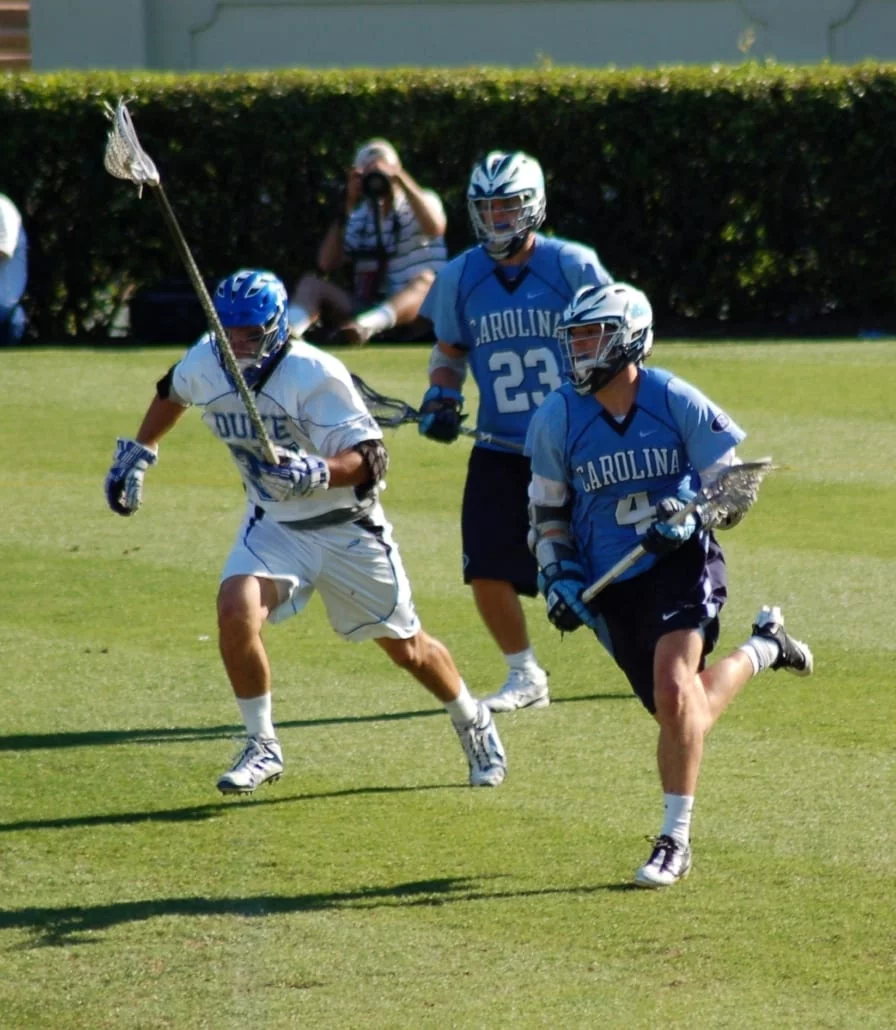 Duke Lacrosse long stick midfielder LSM pursues the NorthCarolina midfielder carrying the ball