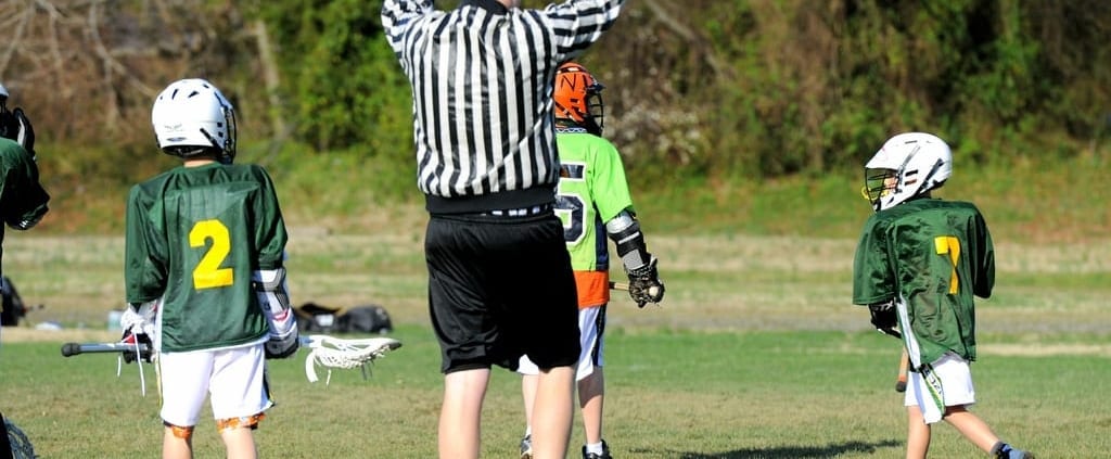 youth lacrosse official signals a goal