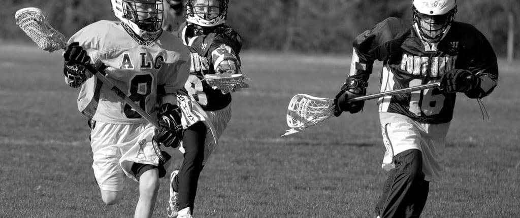youth lacrosse defenders chasing the ball