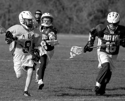 youth lacrosse defenders chasing the ball